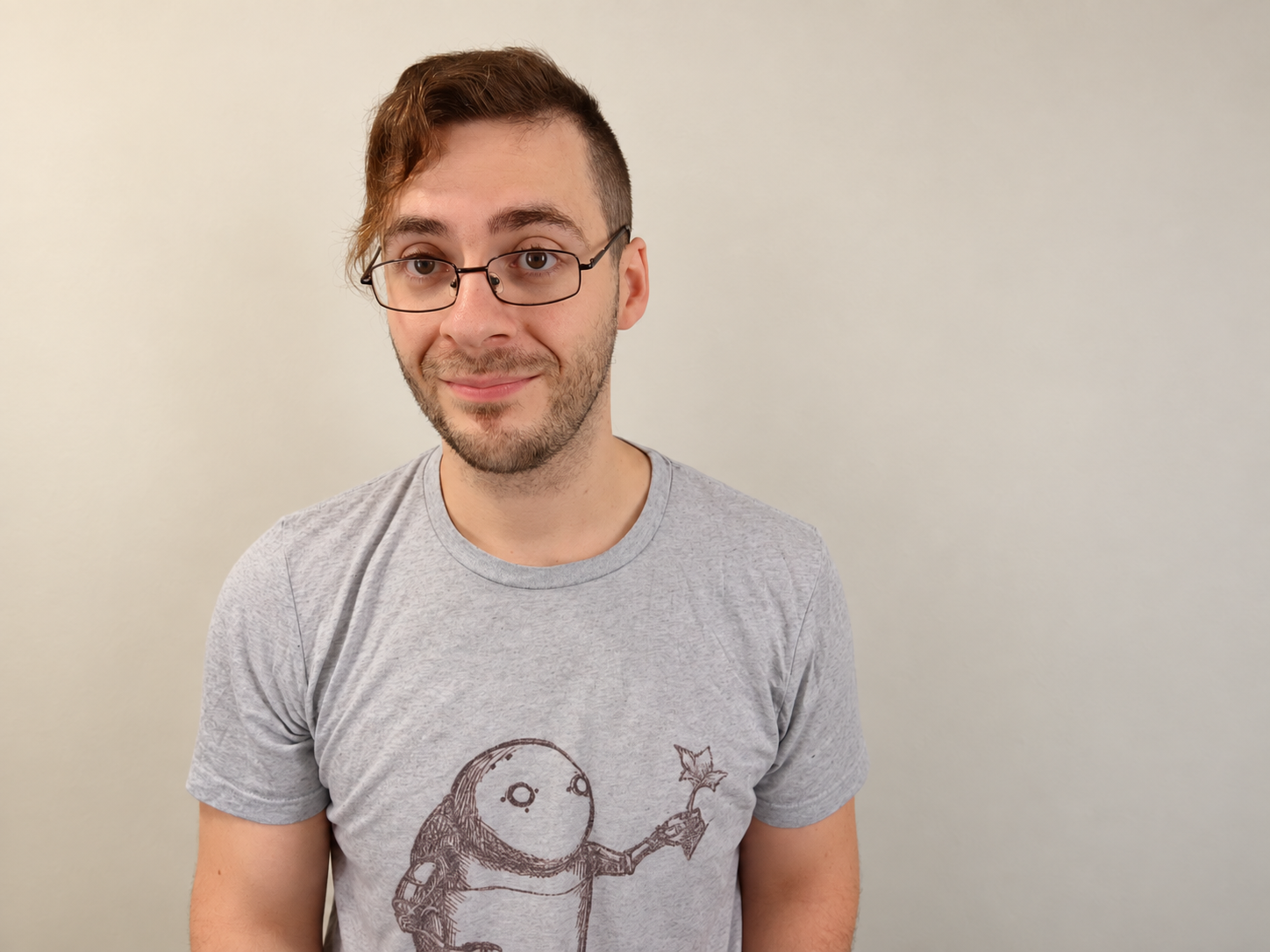 Domenic Angelino wearing glasses and a gray illustrated T-shirt